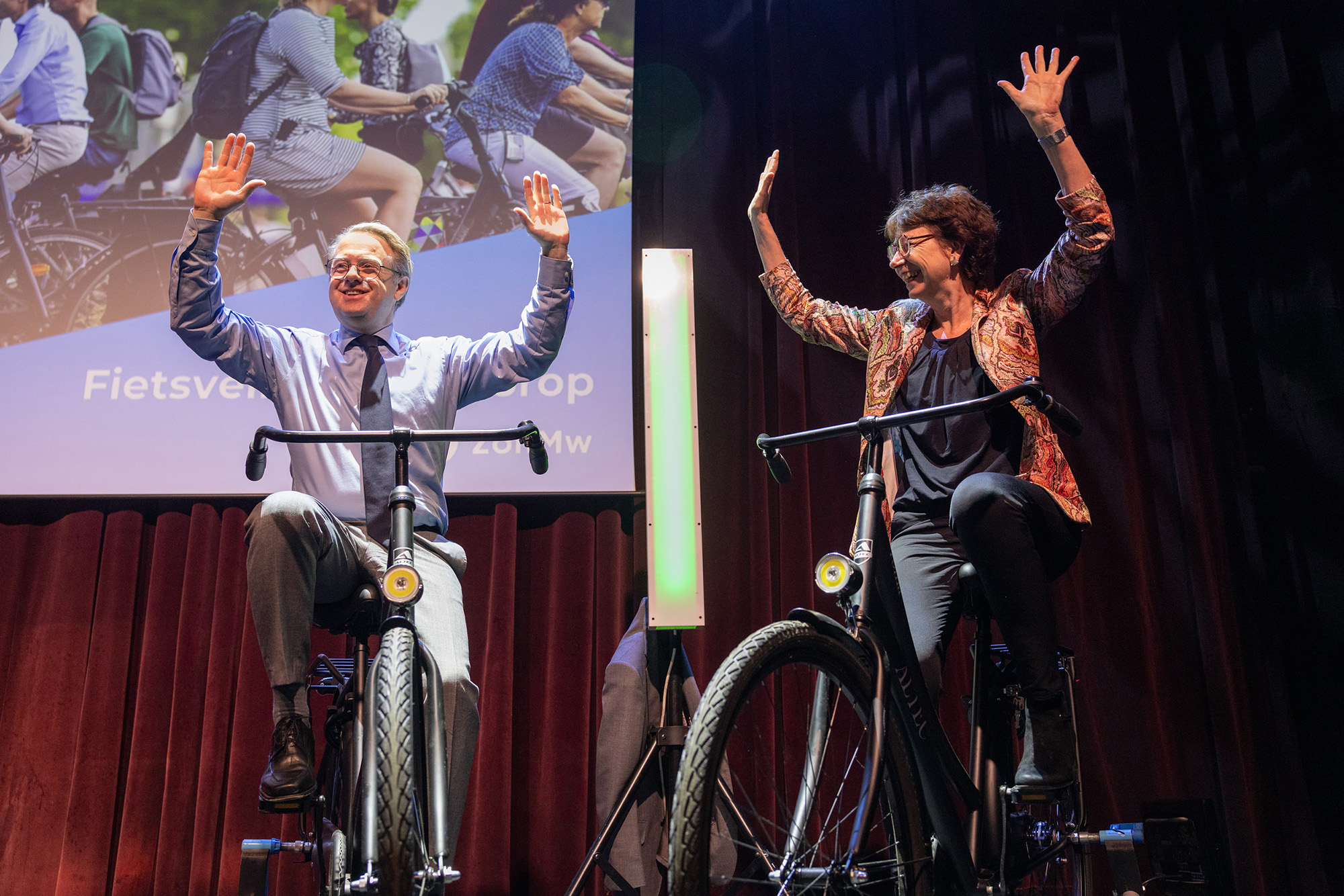 een man en vrouw op fietsen op een podium met handen in de lucht
