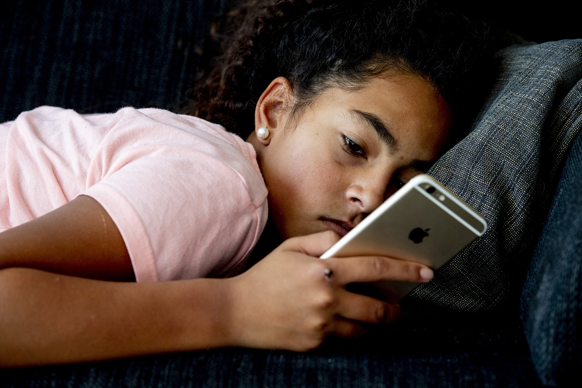 Tiener ligt verveeld op telefoon te kijken