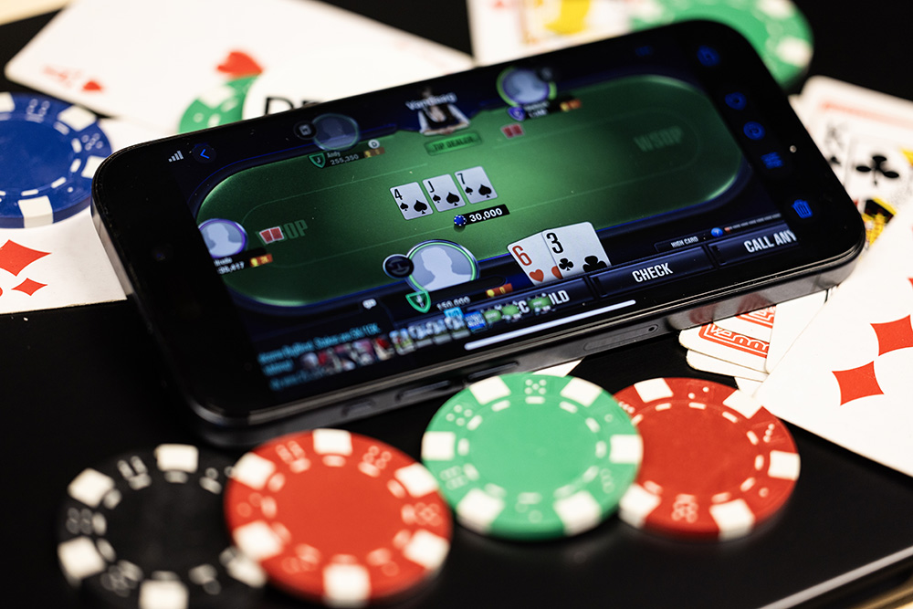 telefoon met een gokspel op het scherm ligt op een goktafel met fiches en speelkaarten